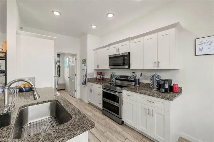 Kitchen featuring dark stone countertops, light wood-style flooring, a sink, and appliances with stainless steel finishes