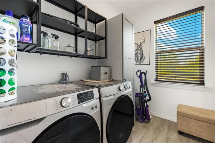 Laundry room featuring washing machine and clothes dryer, baseboards, light wood-style flooring, and laundry area
