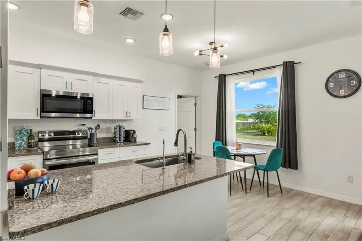Kitchen featuring light wood-type flooring, stainless steel appliances, a sink, visible vents, and white cabinets