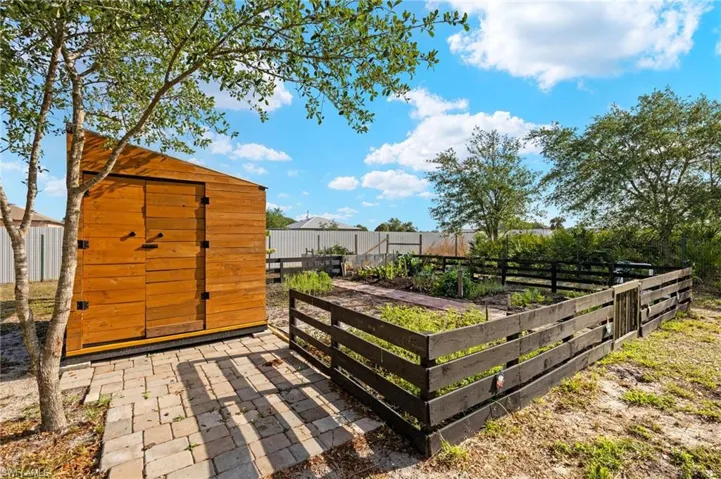 View of shed featuring fence and a vegetable garden