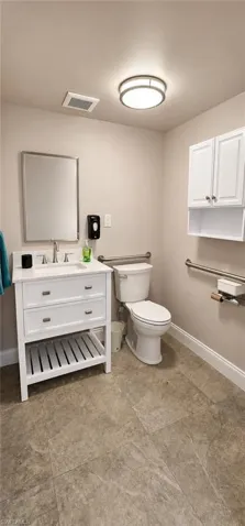 Bathroom featuring a white vanity with a rectangular basin sink, chrome faucet, and integrated storage
