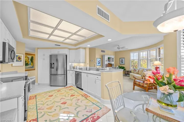 Kitchen with stainless steel appliances, recessed lighting, white cabinetry, light countertops, and open floor plan