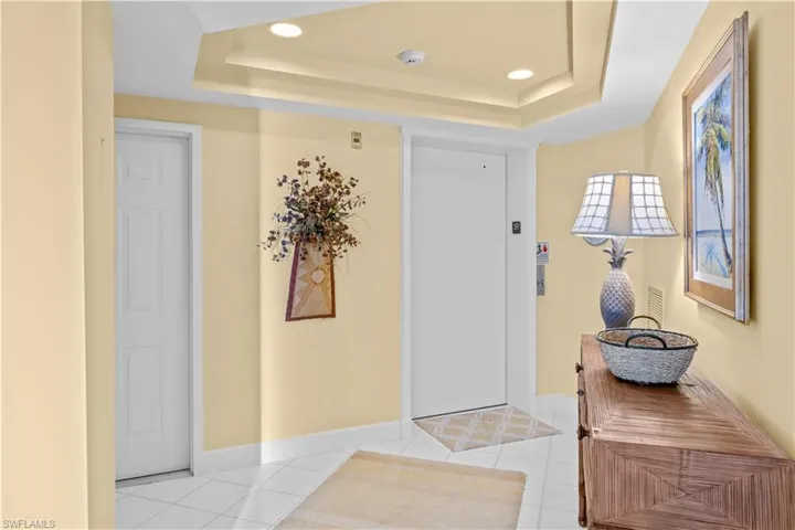 Entryway with elevator, light tile patterned floors, recessed lighting, and a raised ceiling