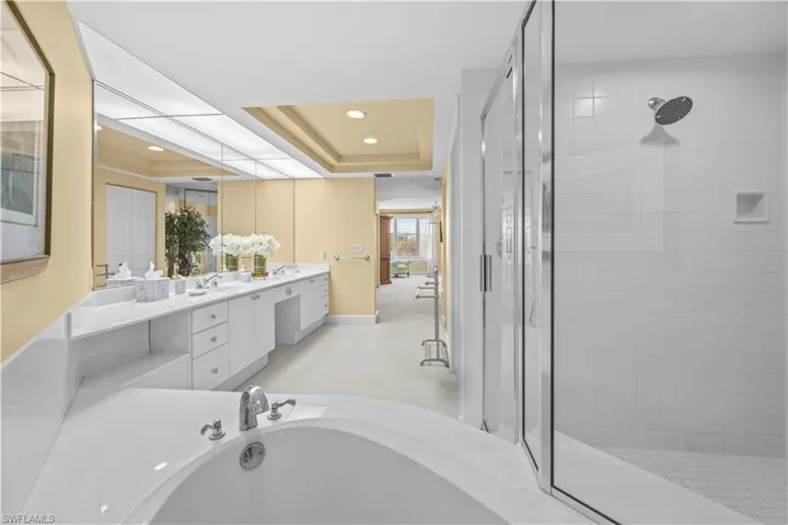 Full bath with a garden tub, a tray ceiling, a shower stall, vanity, and recessed lighting