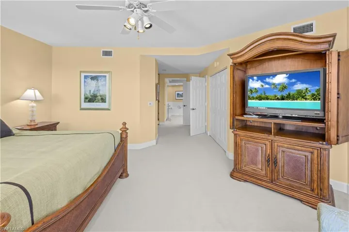 Bedroom with ceiling fan, a closet, and light colored carpet