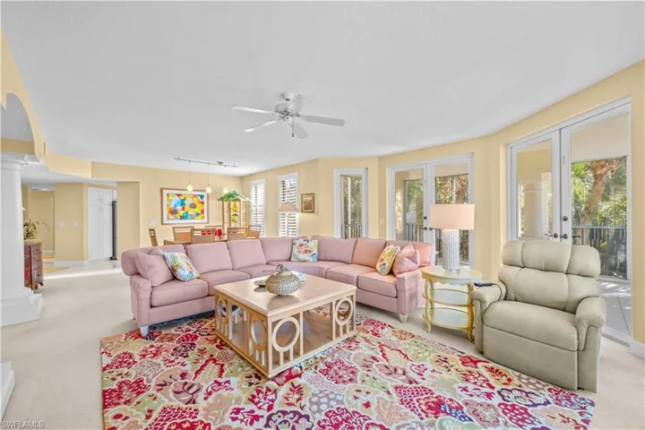 Carpeted living area featuring ornate columns, ceiling fan, track lighting, and french doors