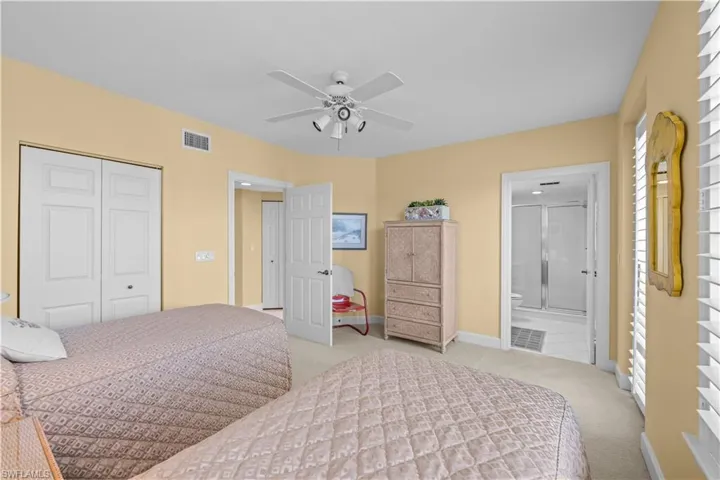 Bedroom with light carpet, a closet, a ceiling fan, and ensuite bathroom