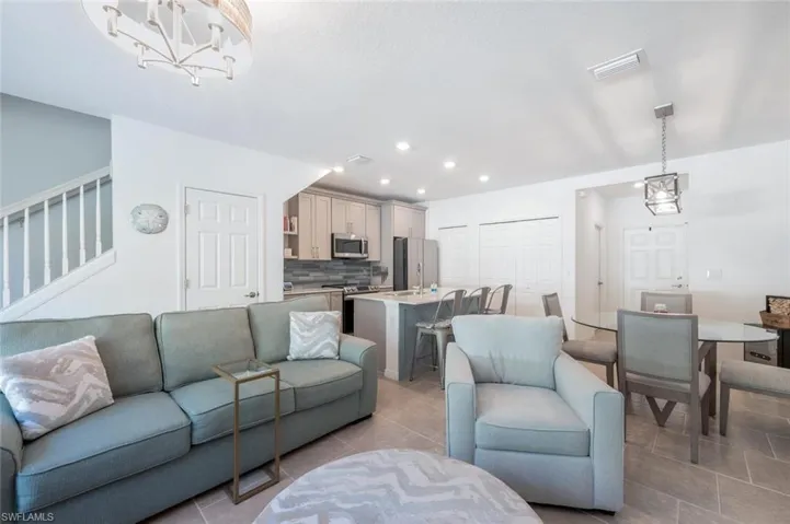 Living room with a chandelier, recessed lighting, light tile patterned flooring, and stairway