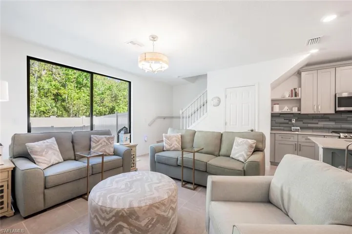 Living area with stairs, light tile patterned flooring, and recessed lighting