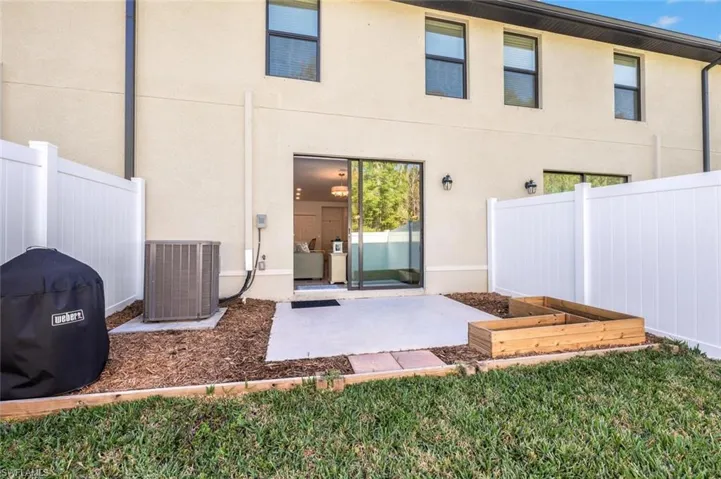 Back of property featuring a vegetable garden, stucco siding, and a patio
