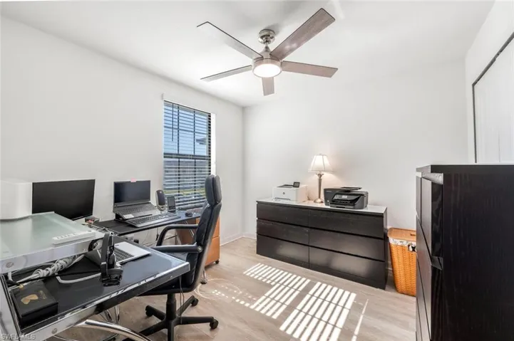 Office with light wood-type flooring and ceiling fan