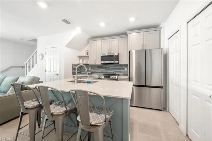 Kitchen with stainless steel appliances, tasteful backsplash, a kitchen bar, recessed lighting, and a kitchen island with sink