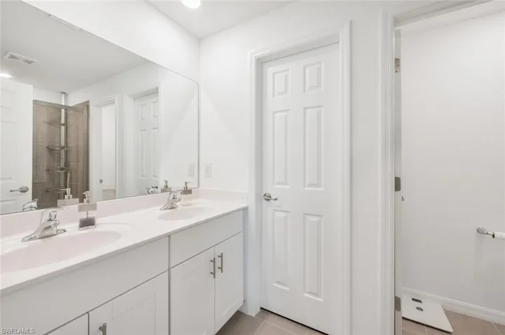 Bathroom featuring double vanity, tile patterned floors, tiled shower, and recessed lighting