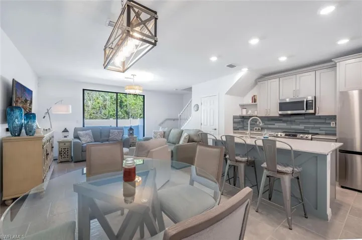 Dining room with light tile patterned floors, recessed lighting, and stairs