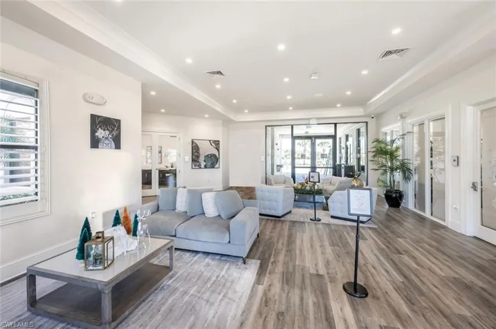 Living room featuring a raised ceiling, french doors, wood finished floors, recessed lighting, and ornamental molding