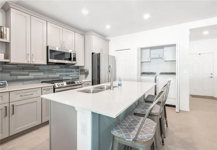 Kitchen featuring separate washer and dryer, decorative backsplash, gray cabinets, recessed lighting, and stainless steel appliances