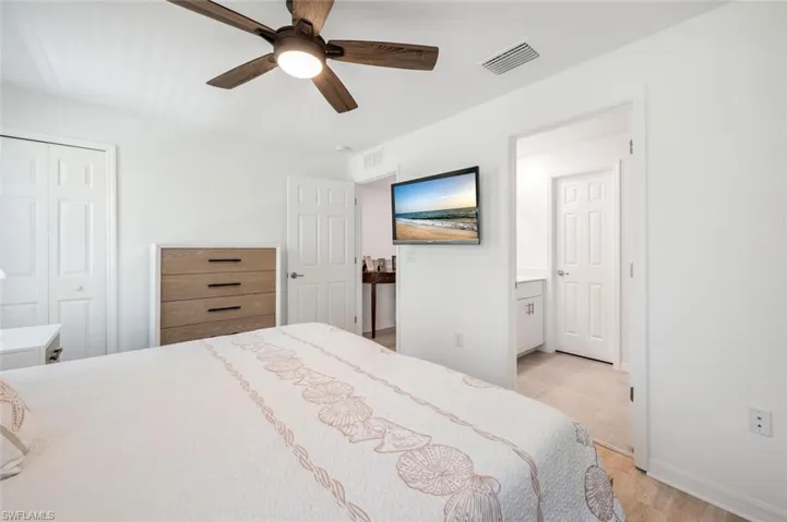 Bedroom with light wood-type flooring, ensuite bathroom, a ceiling fan, and a closet