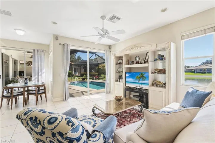 Living area featuring a sunroom, light tile patterned floors, and ceiling fan