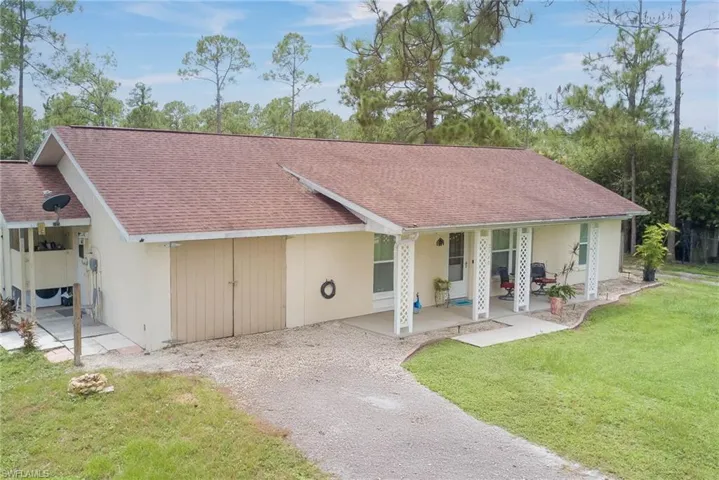 View of front of house featuring a front yard, a shingled roof, and gravel driveway