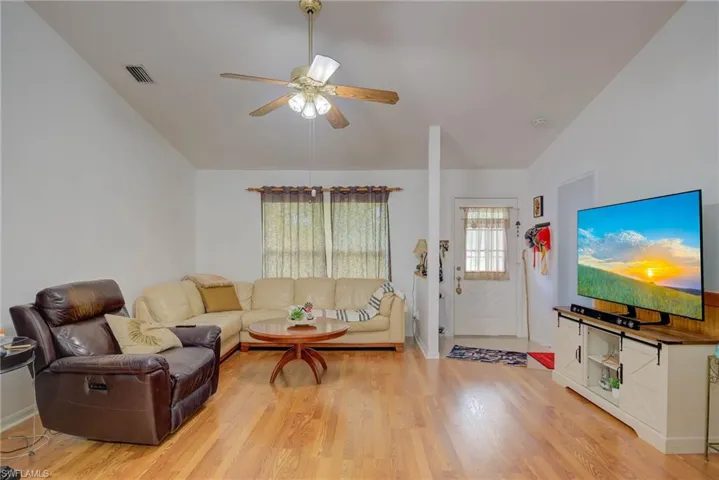 Living area with lofted ceiling, light wood-type flooring, and ceiling fan
