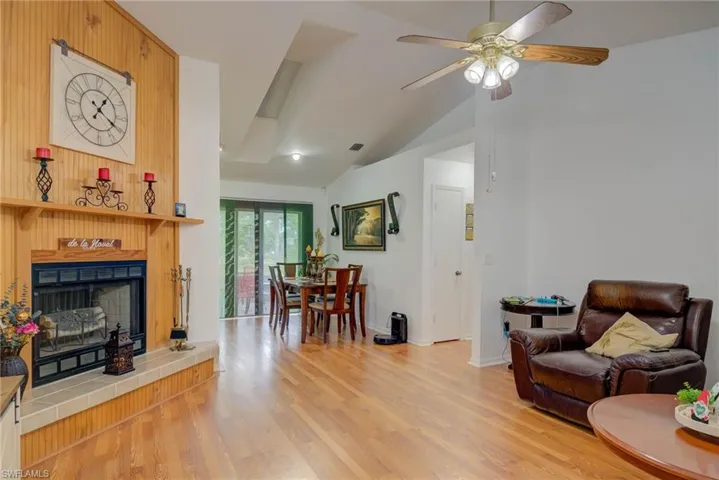 Living area with a fireplace, lofted ceiling, light wood-style flooring, and ceiling fan