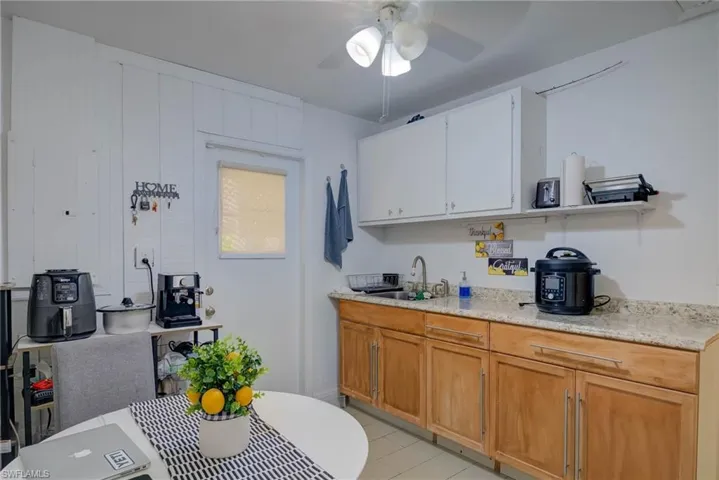 Kitchen featuring white cabinets, light tile patterned floors, ceiling fan, and light stone countertops