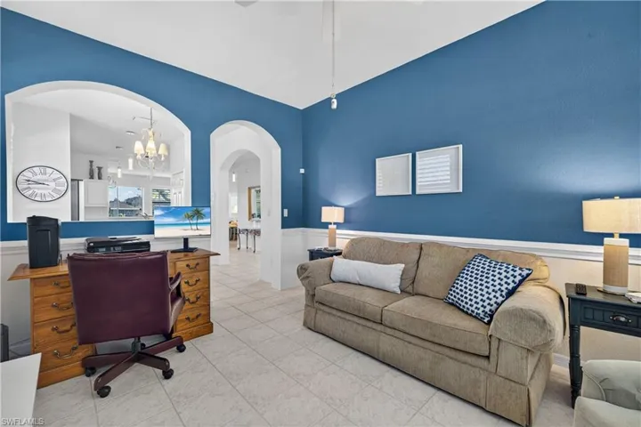 Tiled office space featuring a chandelier, wainscoting, arched walkways, and ceiling fan