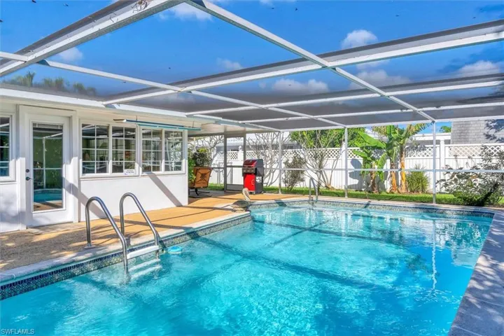 View of swimming pool with area for grilling, glass enclosure, and a patio area