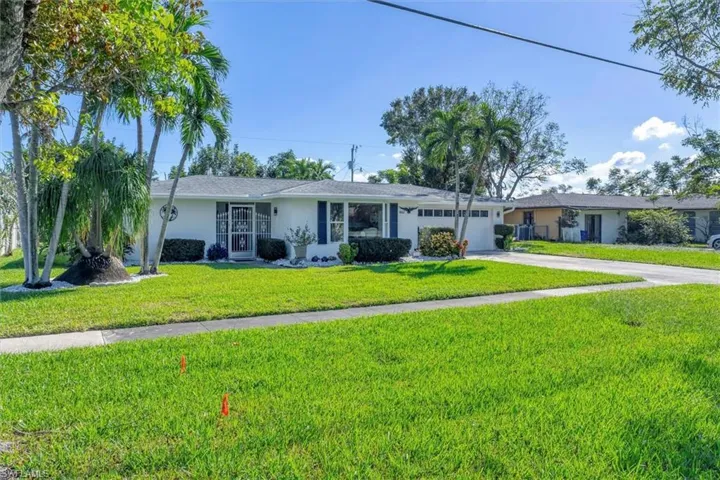 Single story home featuring a garage and a front lawn