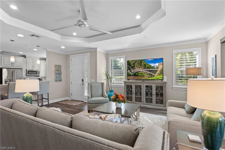 Living room featuring crown molding, dark wood-type flooring, ceiling fan, and a healthy amount of sunlight