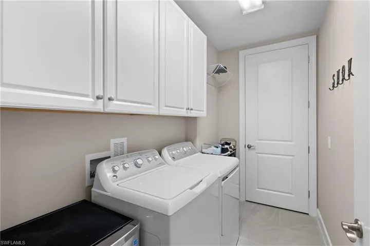 Clothes washing area featuring cabinets and washing machine and dryer