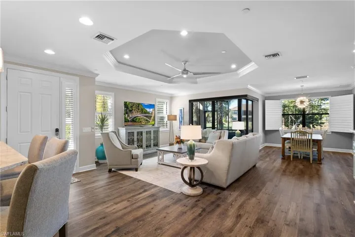 Living room featuring dark hardwood / wood-style floors, a healthy amount of sunlight, ornamental molding, and ceiling fan