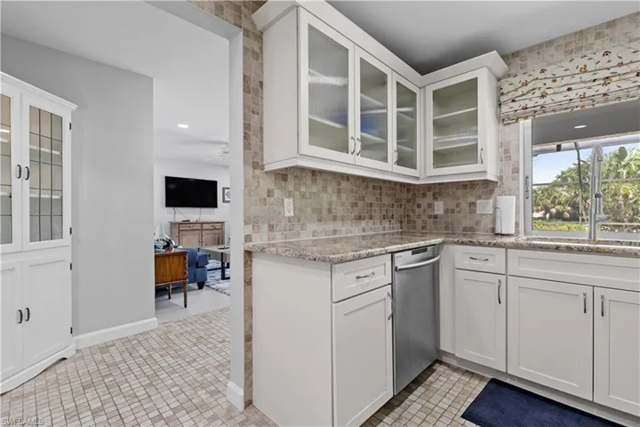Kitchen with tasteful backsplash, stainless steel dishwasher, white cabinetry, and light tile patterned floors