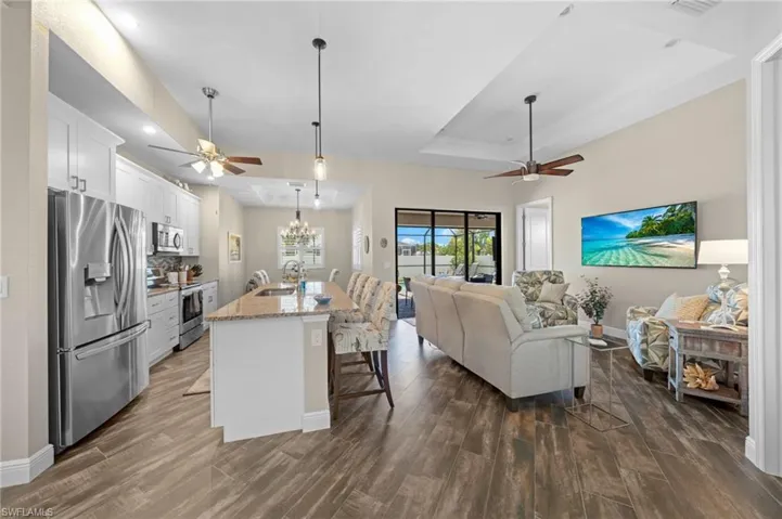 Kitchen with stainless steel appliances, a raised ceiling, a breakfast bar, a ceiling fan, and recessed lighting