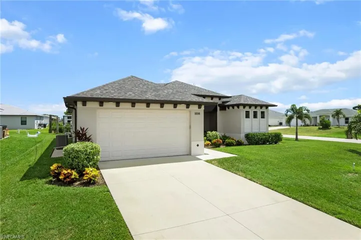 Prairie-style house with a front yard, stucco siding, an attached garage, a shingled roof, and concrete driveway