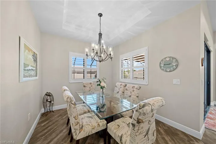 Dining room featuring a raised ceiling, dark wood finished floors, and a chandelier