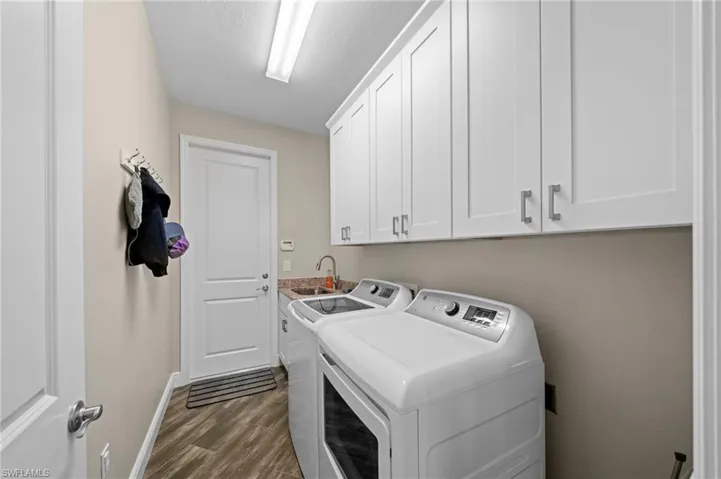 Laundry area featuring washer and clothes dryer, dark wood-style floors, cabinet space, and a textured ceiling