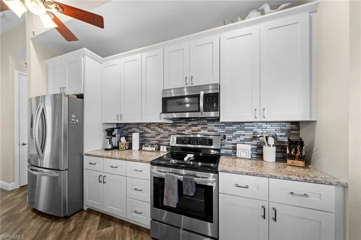 Kitchen with stainless steel appliances, white cabinetry, and tasteful backsplash