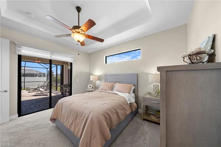 Bedroom featuring a tray ceiling, carpet, access to outside, and a ceiling fan