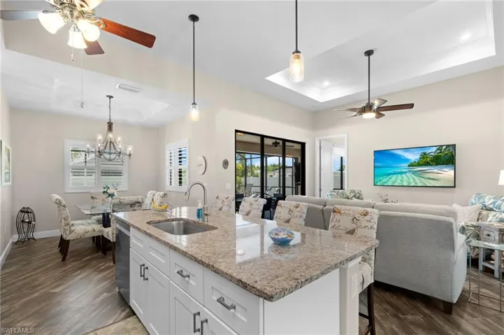 Kitchen featuring ceiling fan, a tray ceiling, white cabinetry, and light stone counters