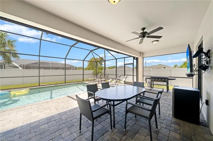 Fenced backyard with a sunroom, glass enclosure, ceiling fan, a patio area, and outdoor dining space