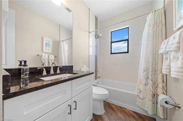 Bathroom featuring shower / bath combo, dark wood finished floors, and vanity