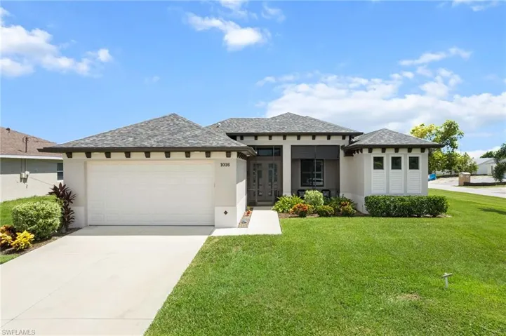 Prairie-style home featuring stucco siding, a front lawn, a garage, driveway, and roof with shingles