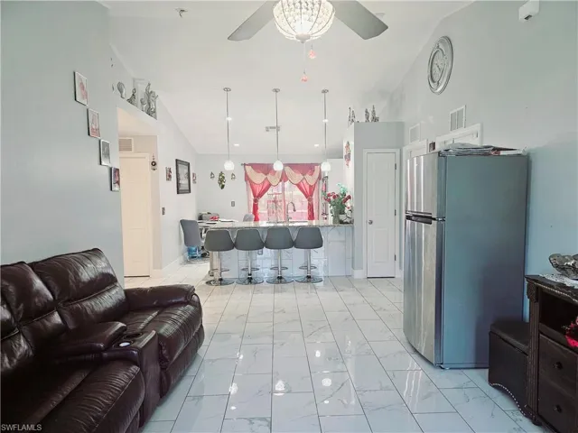 Living room with lofted ceiling, ceiling fan, and sink