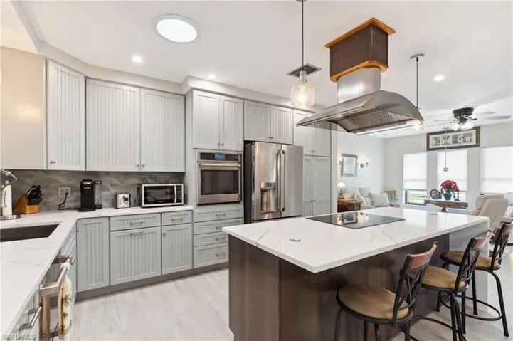 Kitchen with sink, hanging light fixtures, light hardwood / wood-style flooring, ceiling fan, and appliances with stainless steel finishes