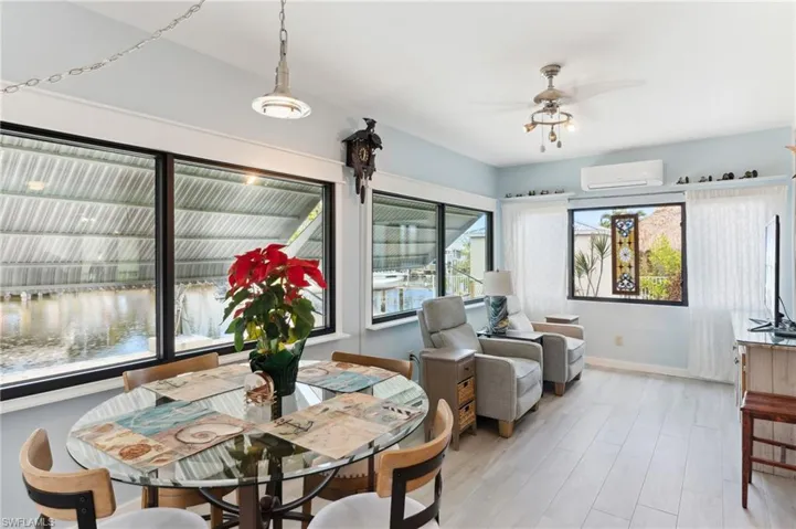 Dining space with a wall mounted AC, ceiling fan, and light hardwood / wood-style flooring