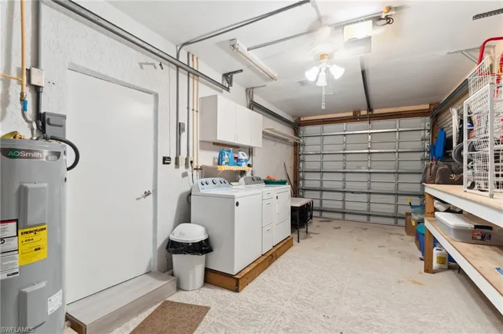 Garage featuring washing machine and dryer and water heater