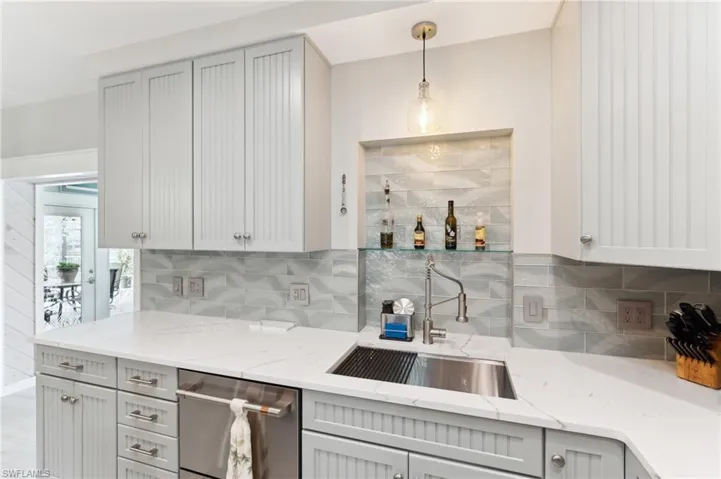 Kitchen with backsplash, gray cabinetry, dishwasher, and decorative light fixtures