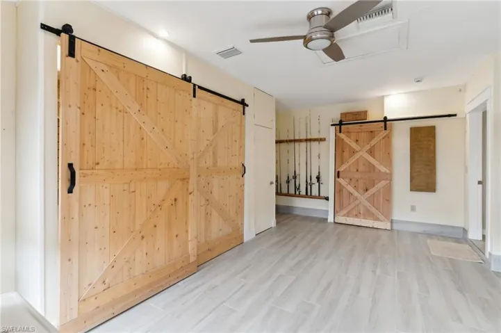 Spare room featuring ceiling fan, a barn door, and light hardwood / wood-style flooring