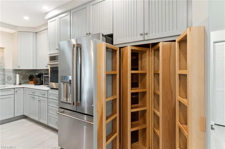 Kitchen with gray cabinets, decorative backsplash, light hardwood / wood-style flooring, and appliances with stainless steel finishes